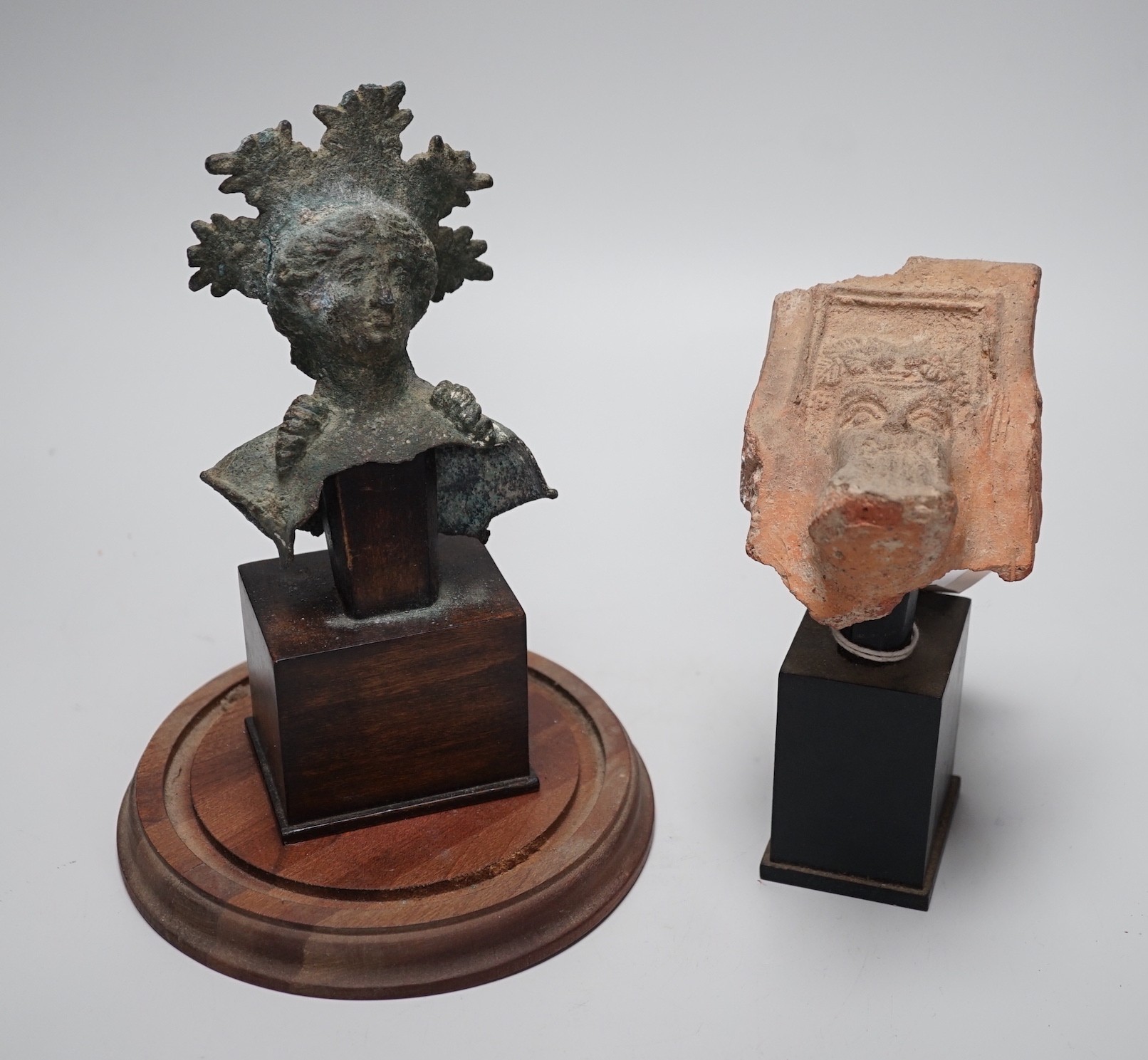 A Hellenistic terracotta brazier fragment with Dionysos mask, 2nd-1st century BCE., and a bronze fragment of a votive figure or figure of a goddess, probably Etruscan, 13.5 cm high excluding stand